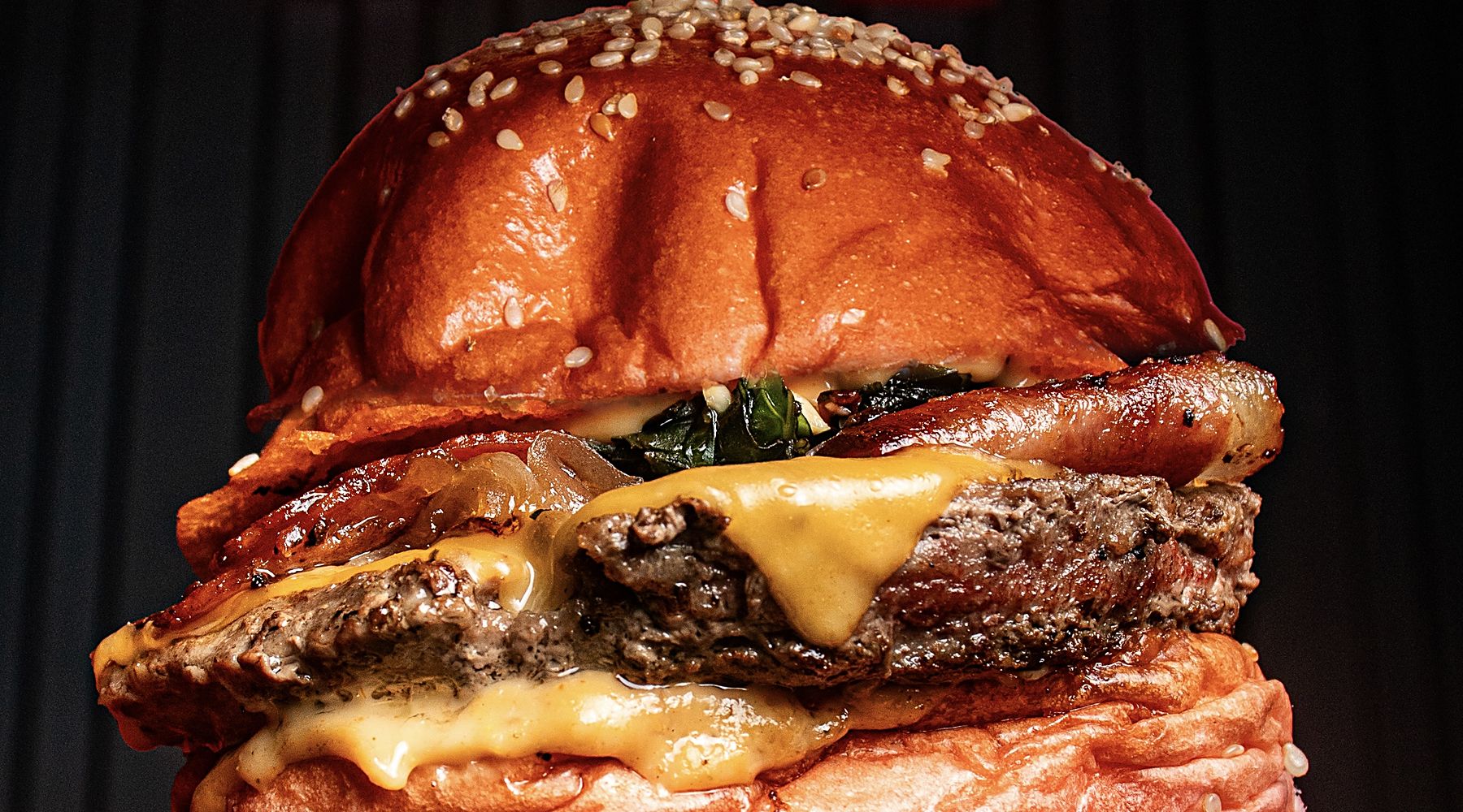 Hamburguesa Muncher recién armada sobre la plancha, con cebolla caramelizada y queso derretido