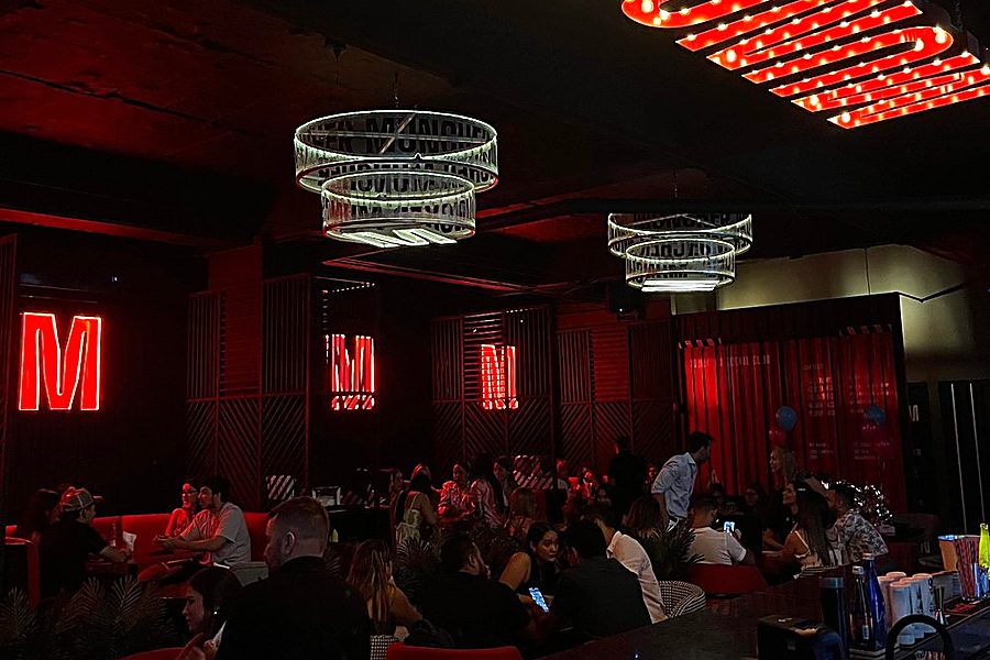 Salón lleno en Muncher Calle 84, con el aviso de bombillos y los letreros de neón encendidos